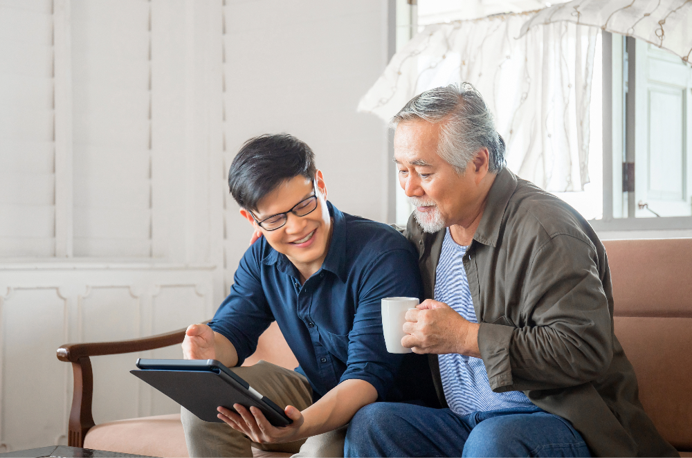 Father and son sitting on couch looking at tablet