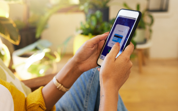 Person using a smartphone with a login screen, indoors with plants in the background.